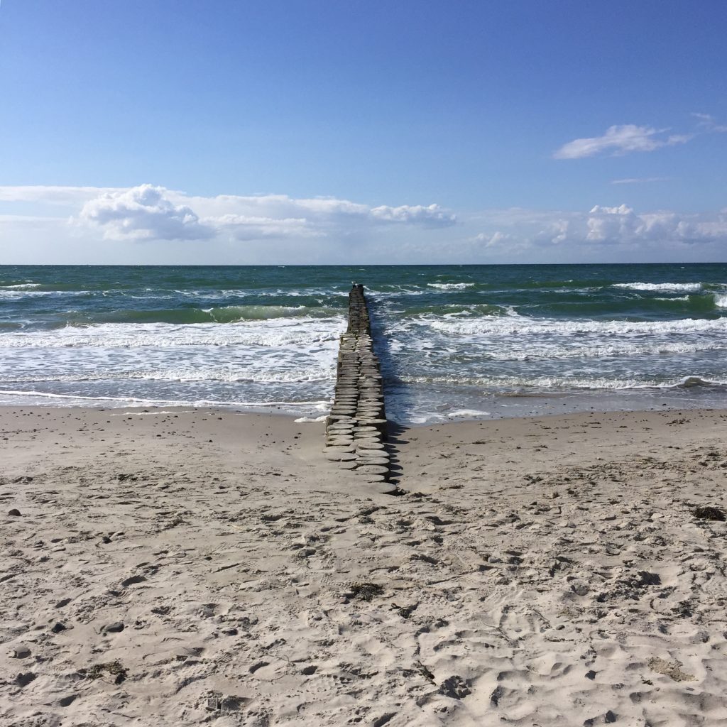 eine Buhne aus Holzbohlen ragt vom Strand in die Ostsee